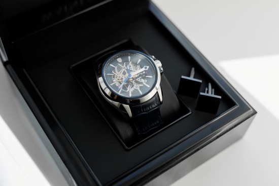 Entendiendo las fichas técnicas de los relojes Reloj automático con esfera esqueletada en caja de presentación de lujo, junto a gemelos negros